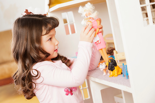 A little girl playing with a dollhouse.