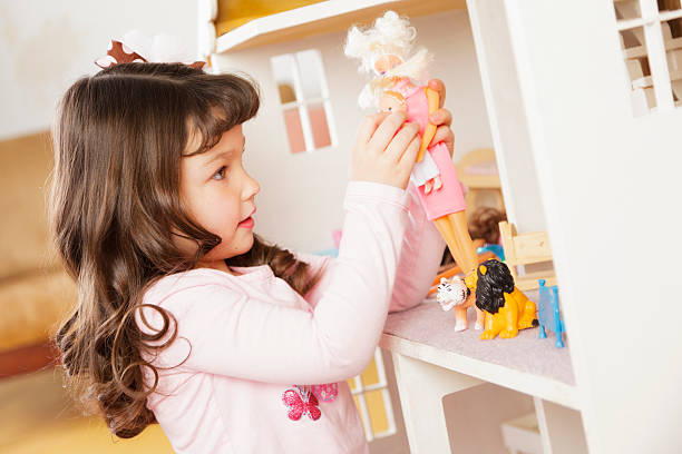 Little Girl with Dollhouse A little girl playing with a dollhouse. doll photos stock pictures, royalty-free photos & images