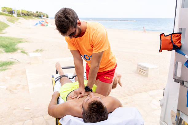 Lifeguard performing cardiopulmonary resuscitation on a man on a stretcher stock photo
