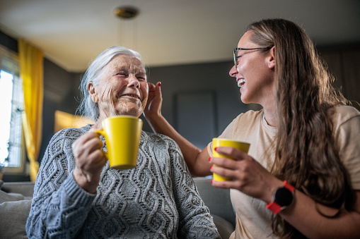 granny and granddaughter enjoying morning coffe and talking at home