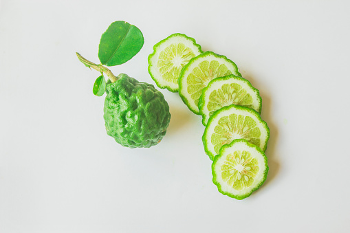 Kaffir lime fruit with green leaves, isolated sliced kaffir lime on white background
