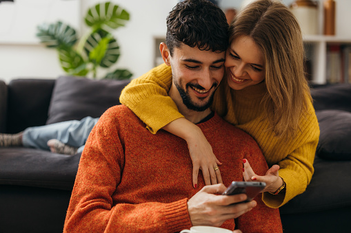 Man and a woman hug and look at the phone together