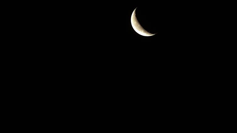 Time lapse of rising crescent moon on black cloudless background