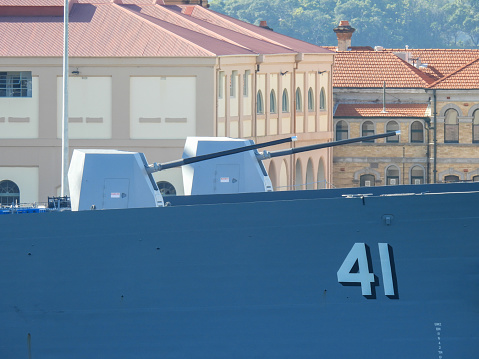 The Mk45 5-inch 62 calibre guns of HMAS Brisbane (DDG41) and HMAS Sydney (DDG42).  They are two of the three Hobart Class destroyers of the Royal Australian Navy and docked next to each other at Garden Island naval base in Sydney Harbour. The word \