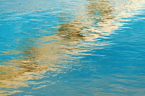 Modern bridge structure reflecting of the river water surface on sunny spring day, selective focus