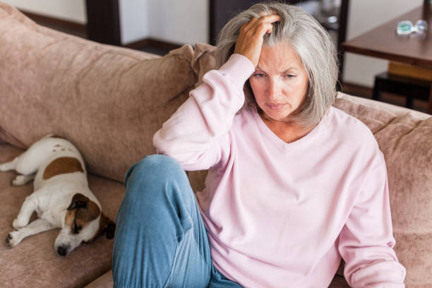 istock Sad pensive middle age woman looking down depressed sitting on the sofa 1613514625