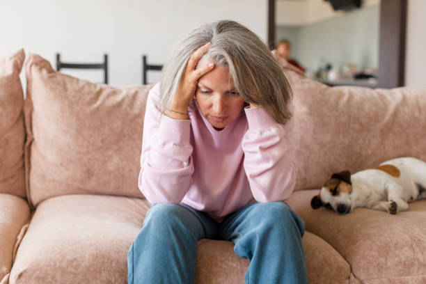 istock Sad pensive middle age woman looking down depressed sitting on the sofa 1613514627