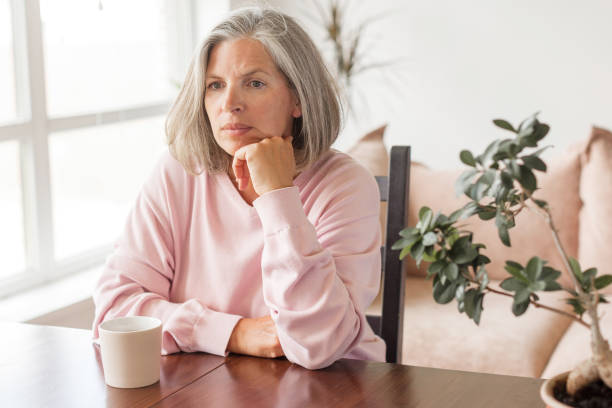 istock Sad pensive middle age woman looking down depressed sitting on the sofa 1613514639