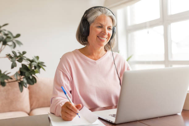 istock Middle aged businesswoman using earphone while sitting behind her laptop 1613514644