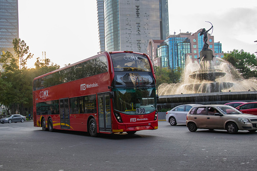 Mexico City, Mexico - 2nd January, 2019: Red double-decker bus Alexander Dennis Enviro500 driving in a city center. This bus was built by Alexander Dennis Limited (ADL) in United Kingdom in 2017. Today is a popular bus in Mexico City. On the back of the bus we see the Huntress Diana Fountain (Fuente de la Diana Cazadora).