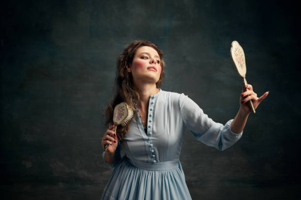 beleza. retrato da mulher aristocrática encantadora usando vestido histórico azul segurando espelho vintage na mão e escovando o cabelo. - mirror women baroque style fashion - fotografias e filmes do acervo