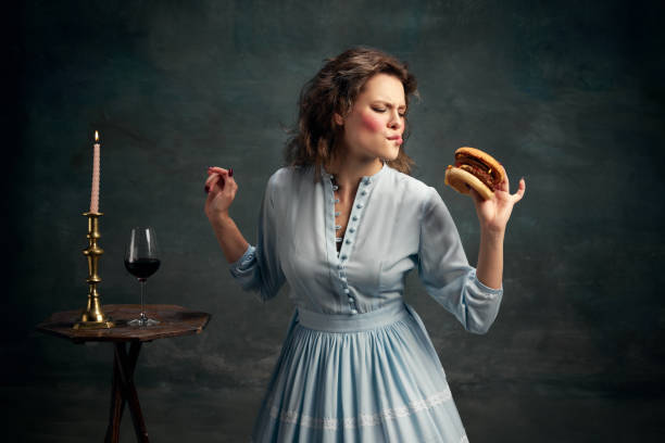 princess. portrait of aristocratic hungry woman wearing blue historical dress eating big hamburger. modern food art. - mirror women baroque style fashion imagens e fotografias de stock