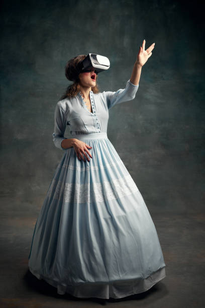 Portrait of surprised aristocratic woman wearing blue historical dress and VR glasses waving hand in air. Gadgets. Queen of technologies. Portrait of surprised aristocratic woman wearing blue historical dress and VR glasses waving hand in air. Gadgets. Concept of digital lifestyle, future, virtual reality, style, fashion. mirror women baroque style fashion stock pictures, royalty-free photos & images