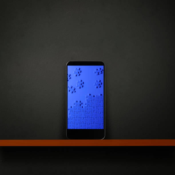 Smartphone with blue jigsaw puzzle displayed on a wooden shelf against dark concrete wall with copy space.