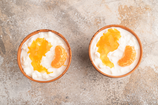 Grained cottage cheese with tangerine jam on brown concrete background. top view, flat lay, copy space.