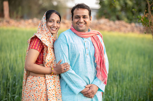 Happy indian rural farmer couple in agricultural field.