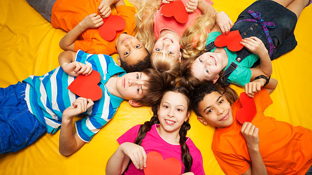 Group of kids laying with red hearts