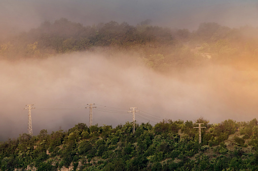 Electrical power lines in the mist in the mountain