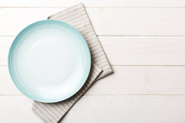 istock Top view on colored background empty round blue plate on tablecloth for food. Empty dish on napkin with space for your design 1613632346