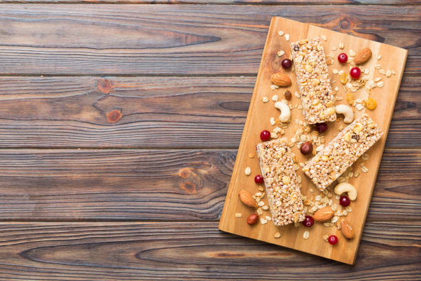 varias barras de granola sobre el fondo de la mesa. barras de granola de cereales. barritas de desayuno de superalimentos con avena, nueces y bayas, de cerca. concepto de superalimento - protein bar cereal oat cranberry fotografías e imágenes de stock