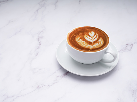 A fresh coffee cup over a marble table. Space for text. Beverage and relaxation concept