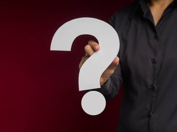 istock Businessman holding a white question mark paper while standing over a red background 1613641043