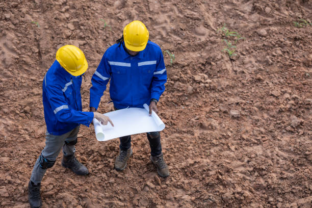 istock Land surveyor team standing working together at construction field consult study looking building location with floor plan 1613647748