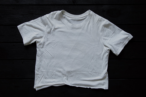 White crumpled t-shirt lies on a black board, fashion and style