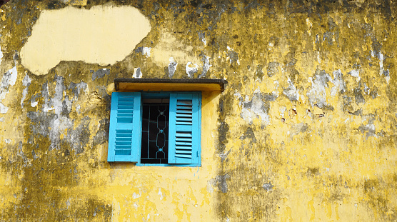 Blue window on old dirty wall in Mekong Delta, southern Vietnam.