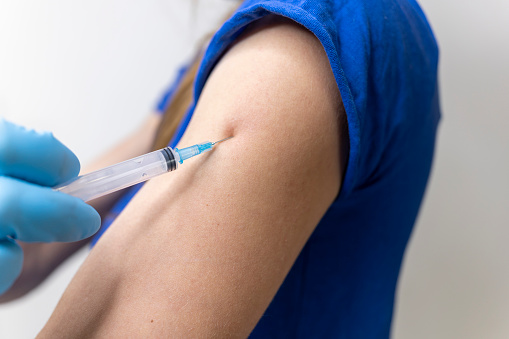 Vaccination against coronavirus. An injection with a vaccine against covid-19. Prevention of influenza disease. Doctor in gloves gives an injection with medicine.