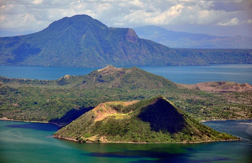 View into the mountain range of the Virunga Volcanoes, a line of 8 volcanoes in the area of the border-triangle between Rwanda, Uganda and the DR Congo. \n\nLeft: Mount Muhabura (4127m)\nRight: Mount Gahinga (3474 m)\nThe lake in the right part of the picture is Lake Ruhonda.\n\nThe Virunga Volcanoes are home of the critically endangered mountain gorilla (gorilla beringei beringei), listed on the IUCN Red List of Endangered Species due to habitat loss, poaching, disease, and war.