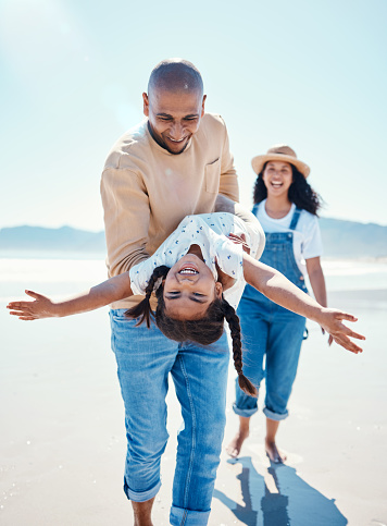 Family, beach and parents play with girl for bonding, quality time and adventure together by ocean. Travel, love and happy mom, dad and child enjoy summer holiday, vacation and relax on weekend