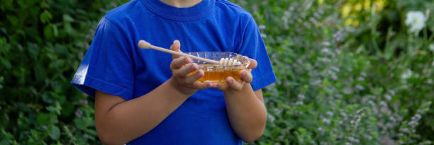 istock the boy eats honey in the garden, honey from his apiary. Selective focus. 1613720483