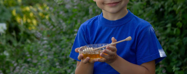 istock the boy eats honey in the garden, honey from his apiary. Selective focus. 1613720488