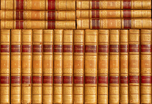 Old library background of leather-bound books with travelogues in luxurious gilt leather binding
