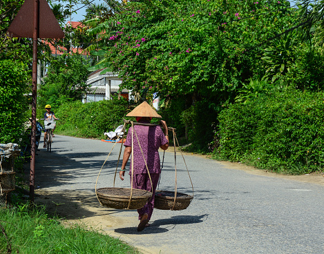 Hoi An, Vietnam - Nov 29, 2015. A woman walking on rural road in Hoi An, Vietnam. Ancient and peaceful, Hoi An is one of the most popular destinations in Vietnam.