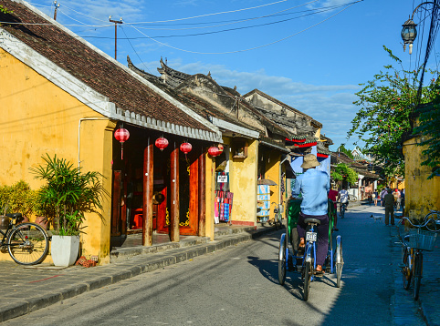 Hoi An, Vietnam - Dec 9, 2015.  People with cyclo on main street in Hoi An Ancient Town, Vietnam. Hoi An is Vietnam most atmospheric and delightful town.