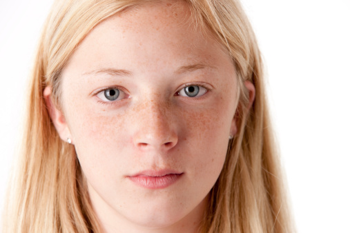 Young girl with green or blue eyes outdoors, looking strait forward to the camera. Shy look. Introspective. Not smiling