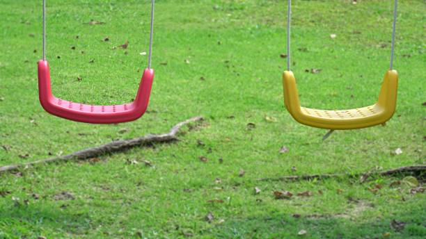 istock Couple empty swing seat hanging in playground. 1613785320