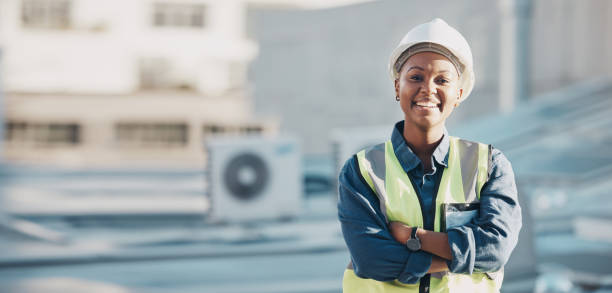 istock Woman, construction worker and portrait with a smile for engineering and building renovation job. Arms crossed, happy and African female employee on a industrial site outdoor for builder project 1613792914