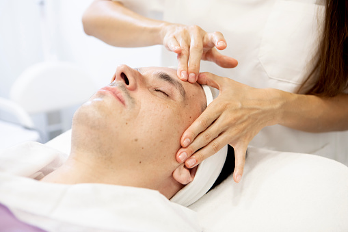 close-up of a beautician's hands performing a facial massage on a man, skin care concept
