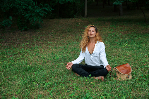Woman Finding Calm as She Meditates on Green Grass