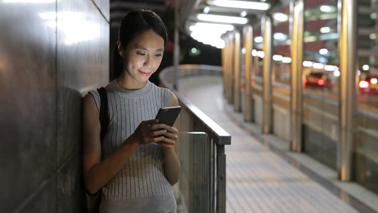 Woman using cellphone at night in Hong Kong city