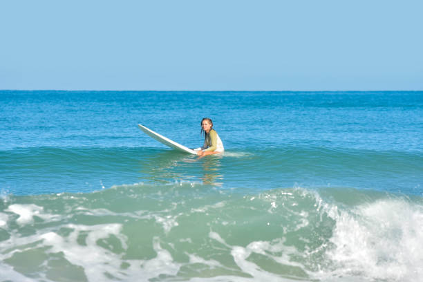 istock Pretty young woman sliding on ocean waves with her surfboard 1613813098