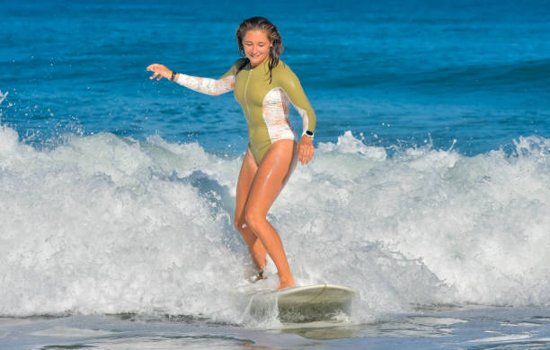 istock Pretty young woman sliding on ocean waves with her surfboard 1613819178