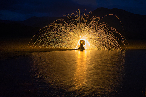 Ring of fire on the lake at night with mountain background.