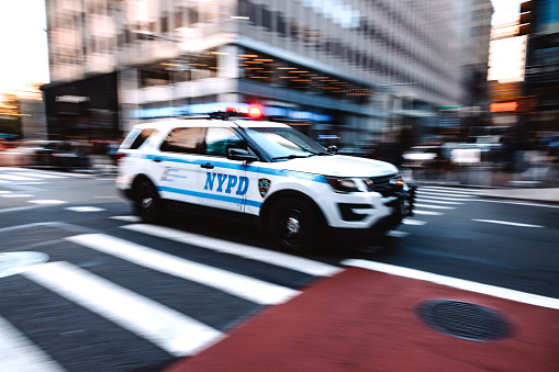 New York City, NY, United States - April 15, 2023: NYPD SUV crossing an intersection on zebra crossing in New York midtown district.