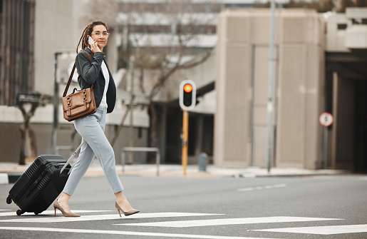 Business, travel and phone call by woman with luggage in city street for networking or work trip. Smartphone, conversation and lady manager in a road with suitcase for traveling appointment in London