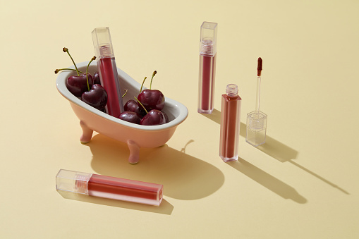 A bathtub filled with cherries decorated with some lipsticks. Cherry is very useful in cosmetic production as an ingredient