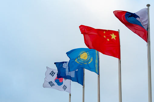 View on the flags of China, Kazakhstan, South Korea, Russia and Commonwealth of Independent States on the background of cloudy sky